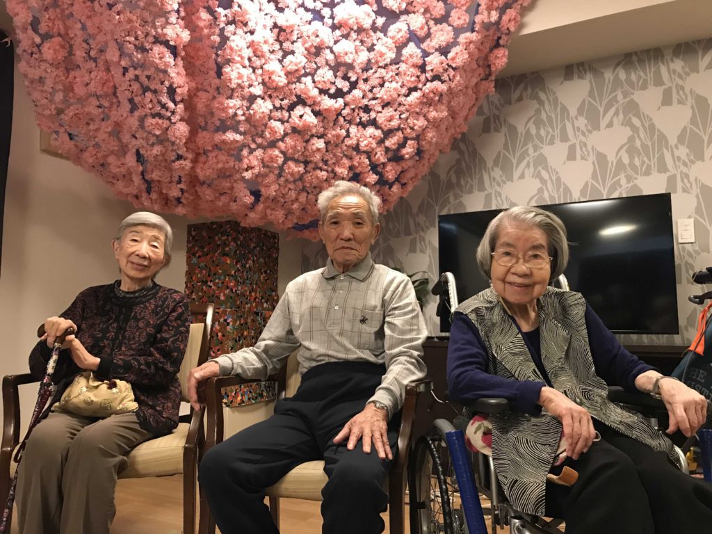 桜の装飾を背景に写る3名