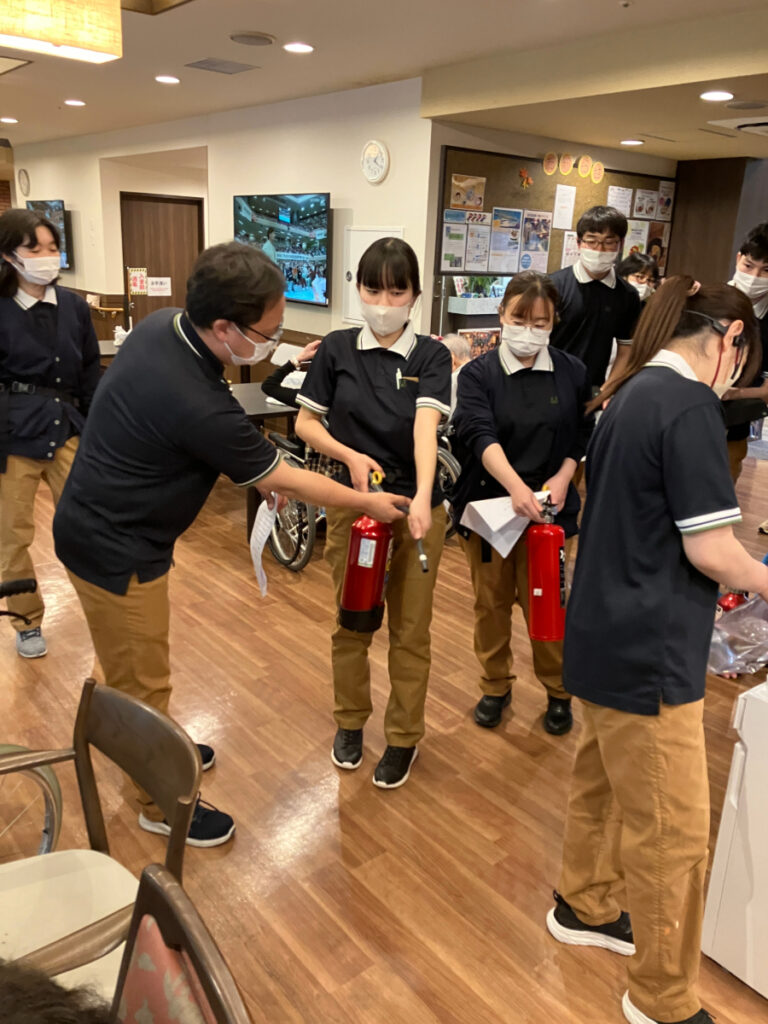 避難訓練で消化器の使い方を学ぶ様子