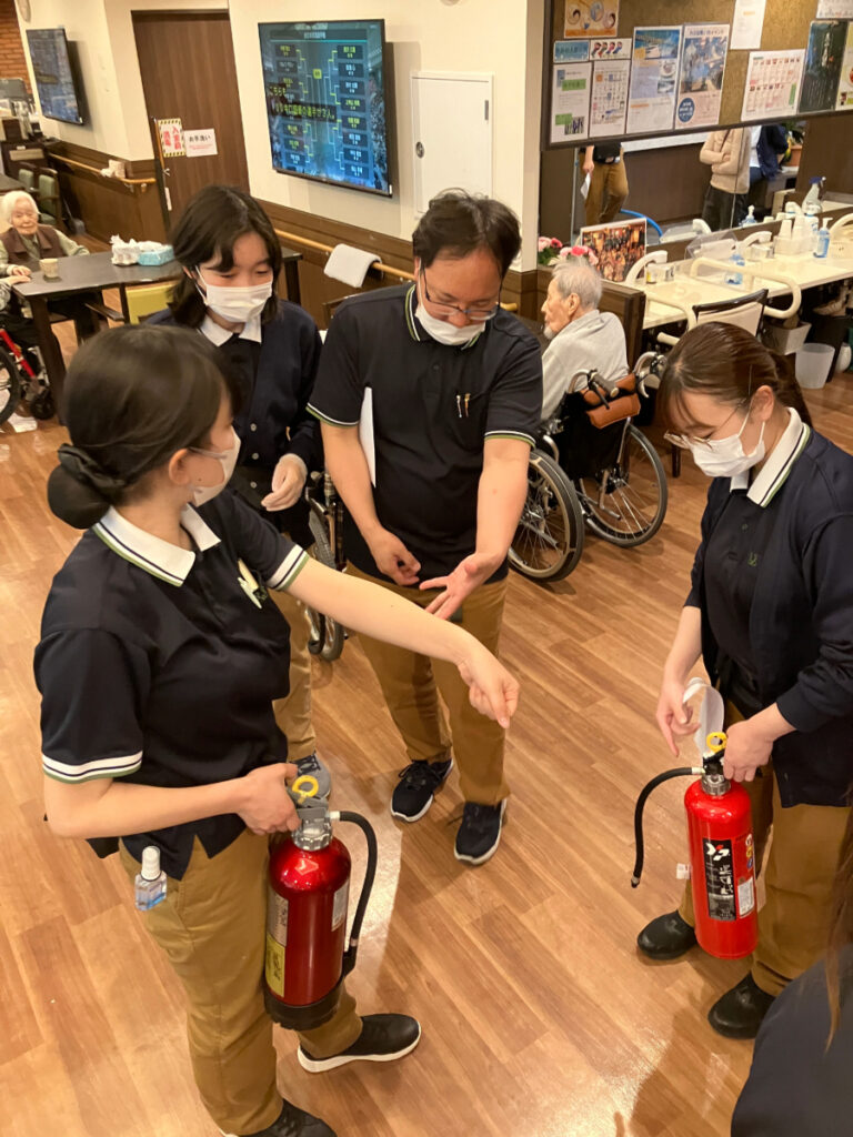 避難訓練で消化器の使い方を学ぶ様子