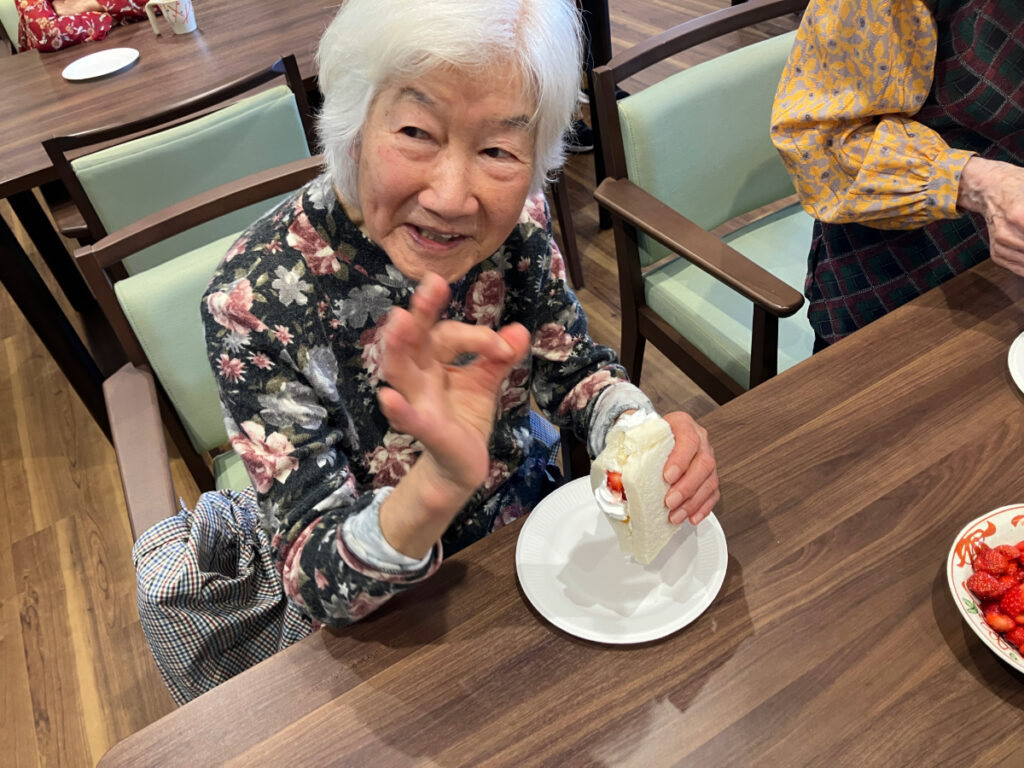 フルーツサンドを食べて笑顔の女性