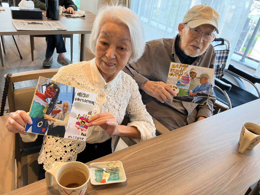 お誕生日会でカードをプレゼントされ笑顔のご入居者