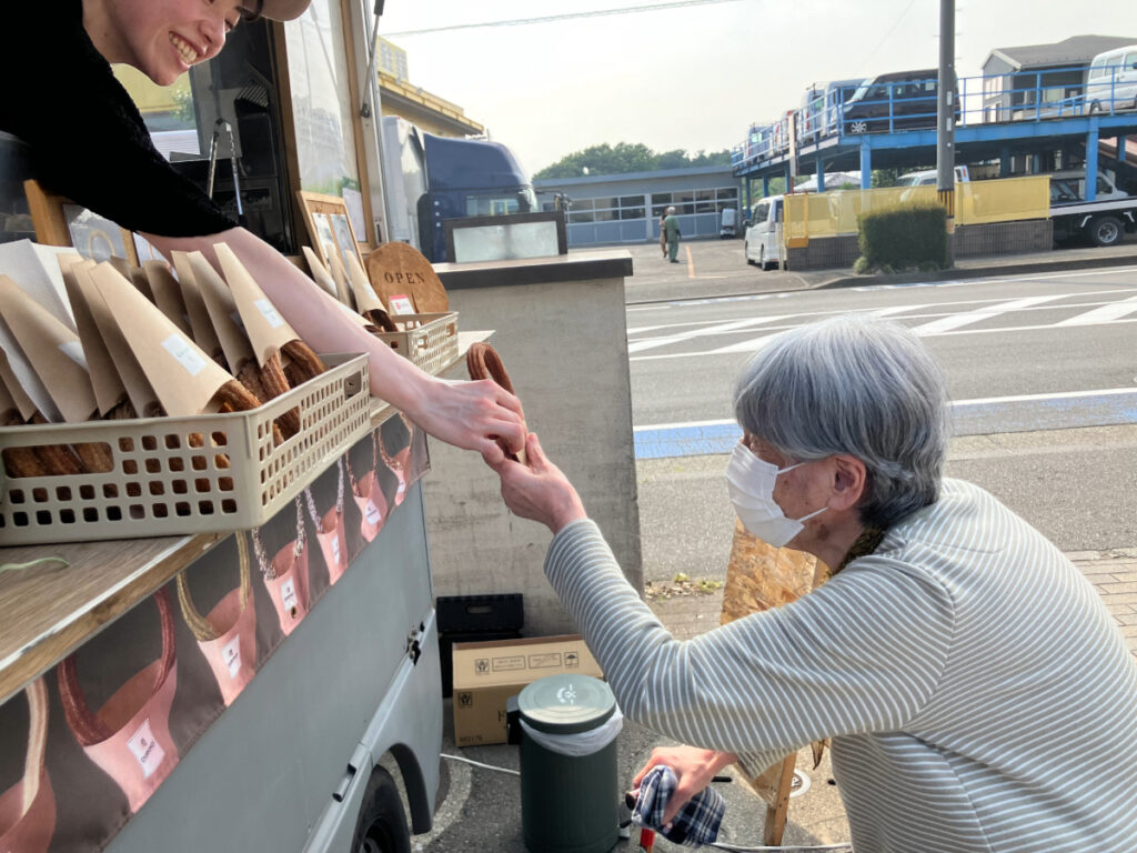 キッチンカーでチュロスを注文受け取る様子