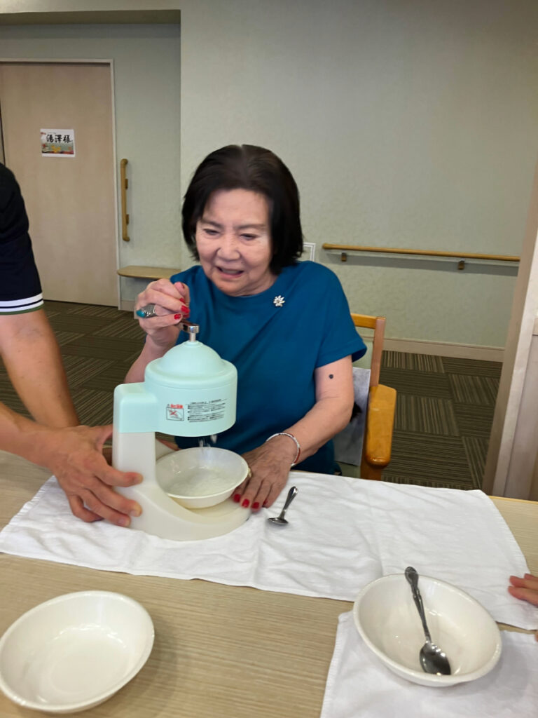 笑顔でかき氷機で氷を削るご入居者