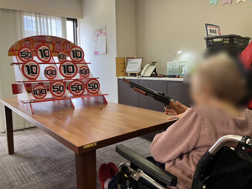 秋祭りの射的で盛り上がるご入居者