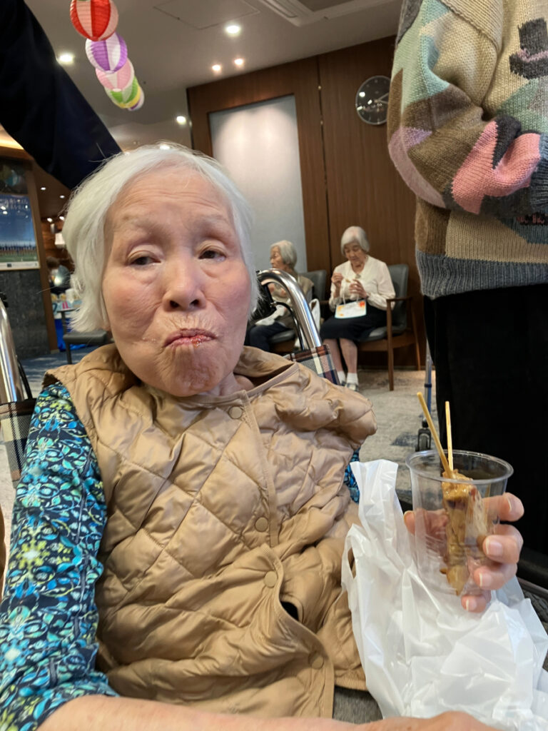 屋台グルメの焼き鳥を食べるご入居者