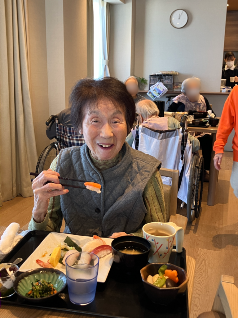 お寿司を食べて笑顔のご入居者