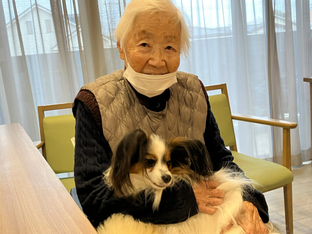 ワンちゃんを抱っこし笑顔のご入居者