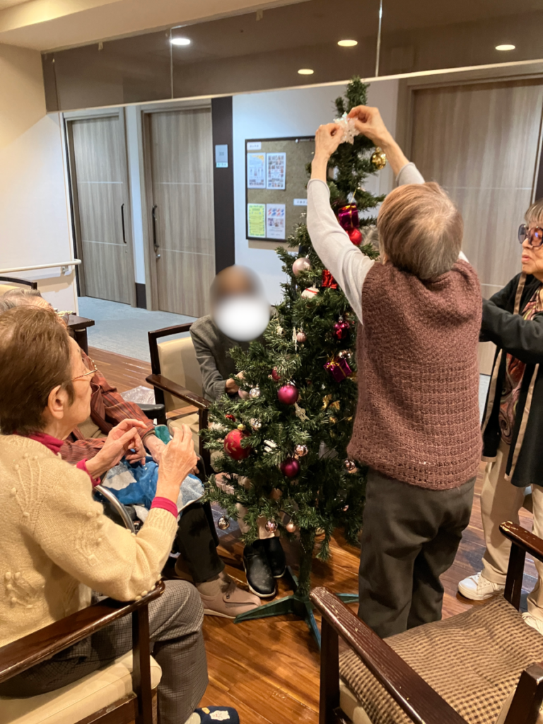 真剣にクリスマスツリーを飾り付けするご入居者