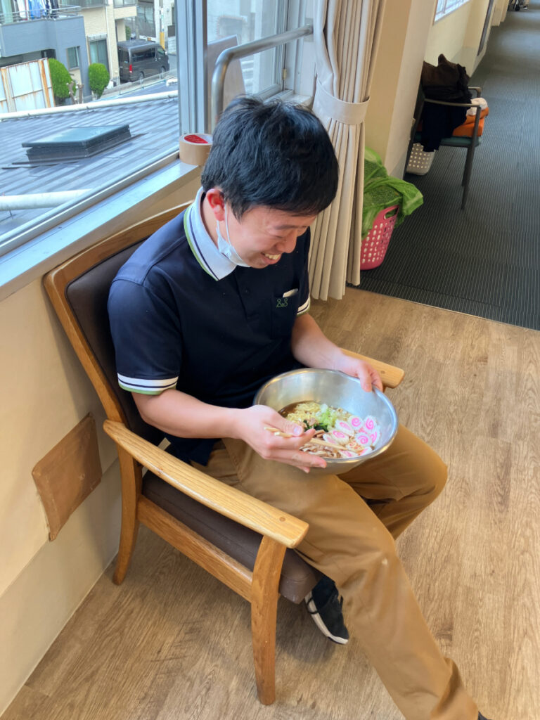 ラーメンを笑顔で食べるスタッフ