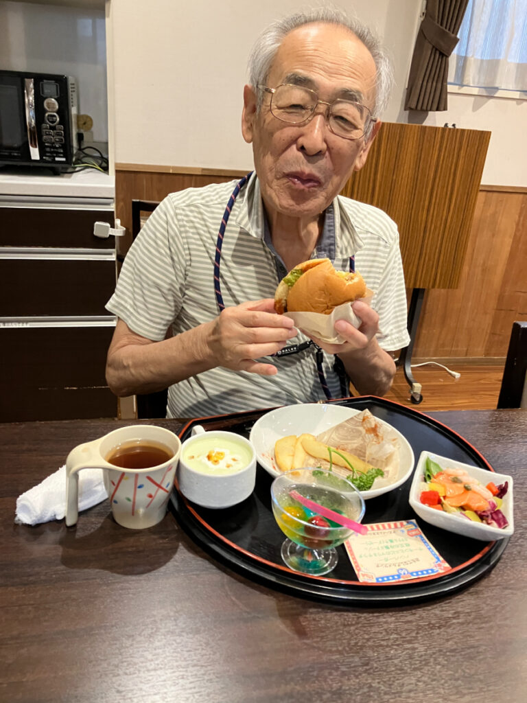 ハンバーガーを笑顔で食べるご入居者