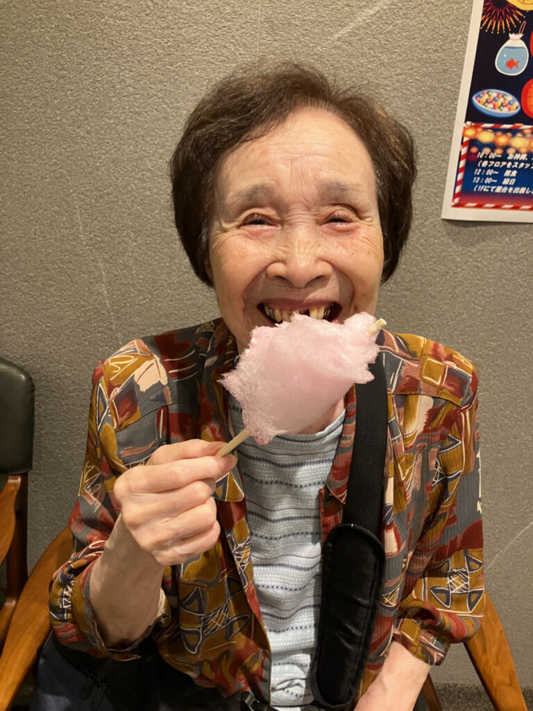 笑顔で綿あめを食べるご入居者