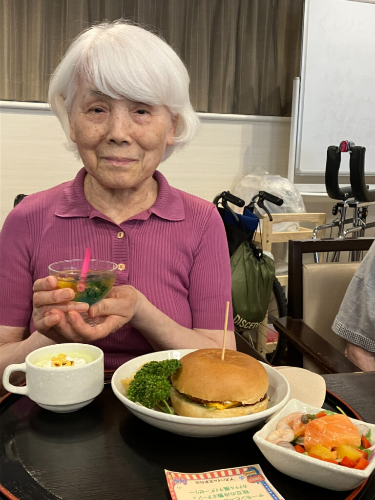 ハンバーガーを笑顔で食べるご入居者